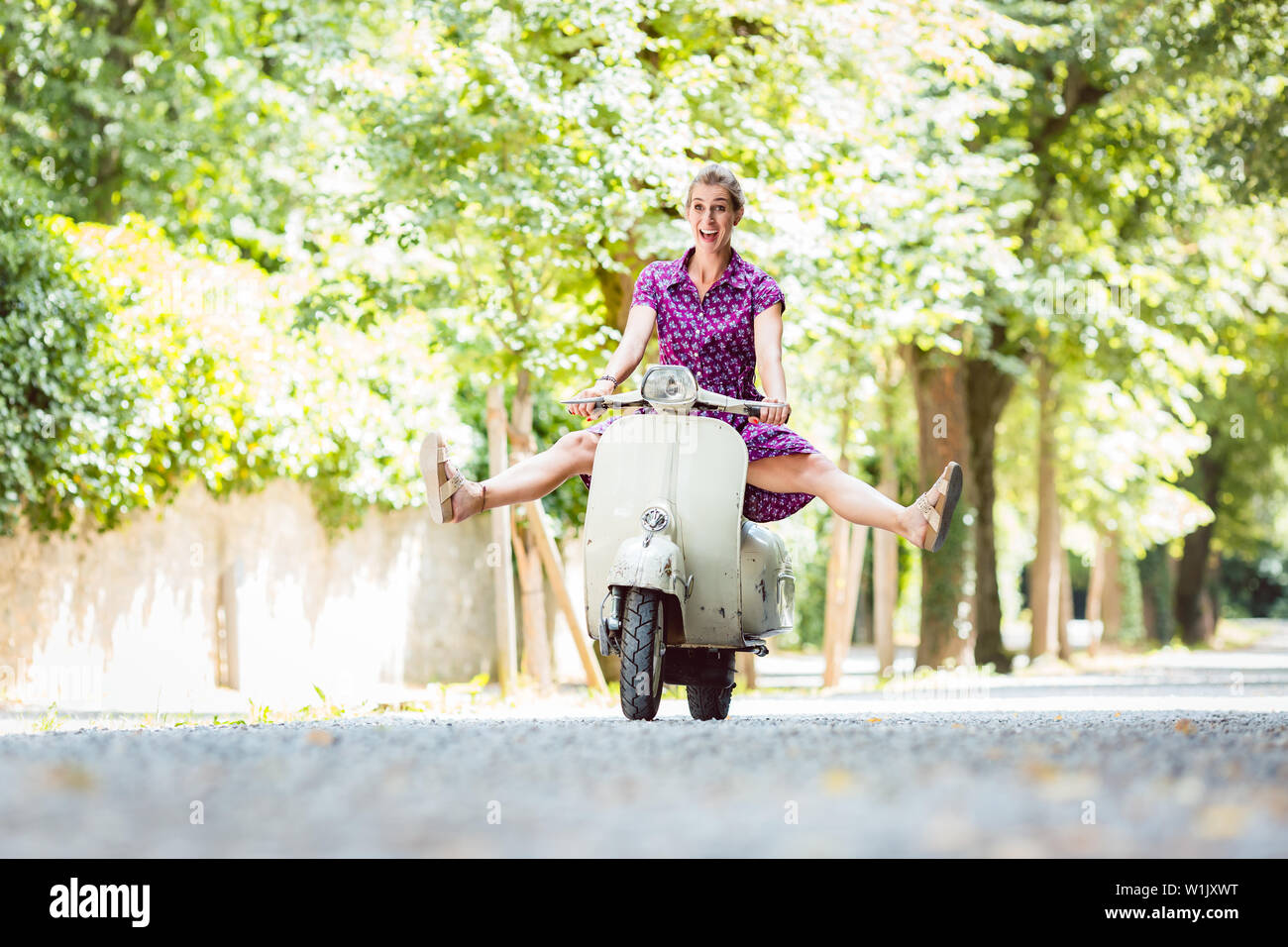 Carefree young woman driving scooter Stock Photo