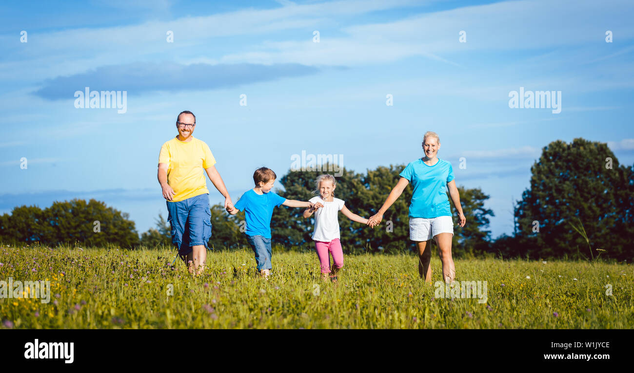 Family holding hands running over meadow Stock Photo