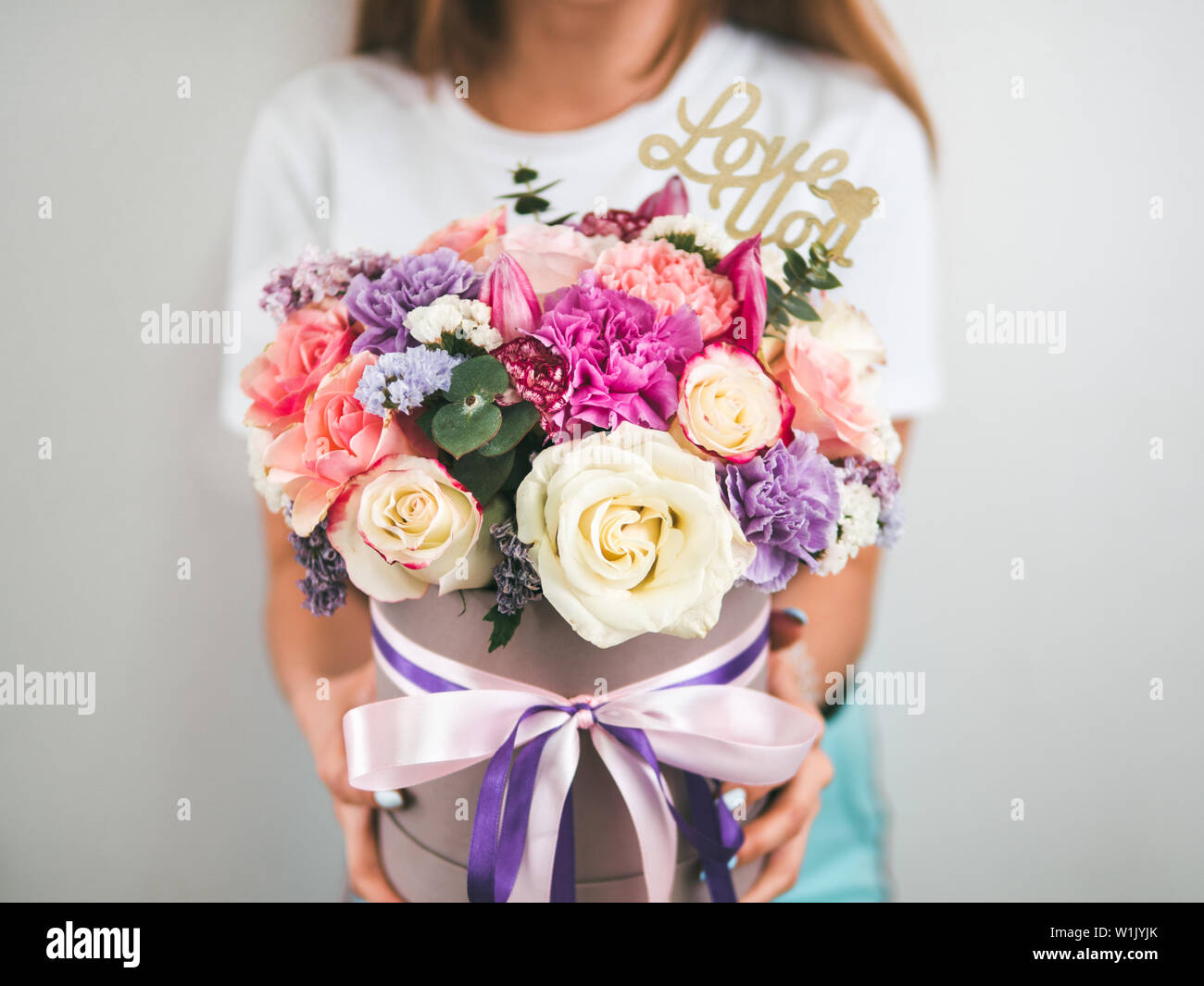 Beautiful bouquet with different flowers in woman hands. Bouquet with roses, dianthus, carnation bush, limonium, lilac and tulip. Shallow DOF, copy space. Top view. Stock Photo