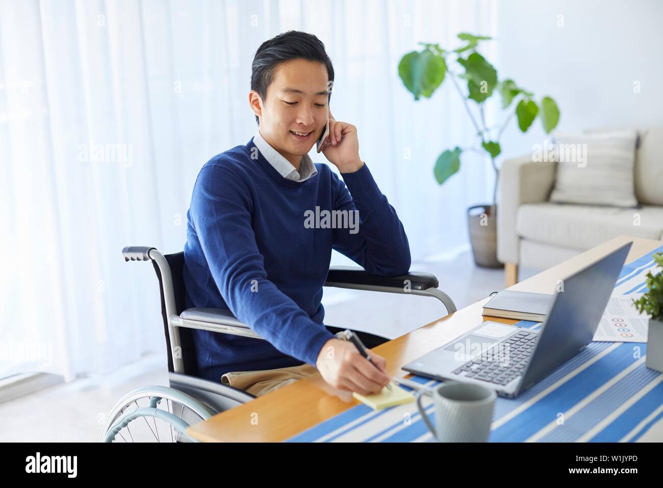 Japanese young man on wheelchair working from home Stock Photo Alamy