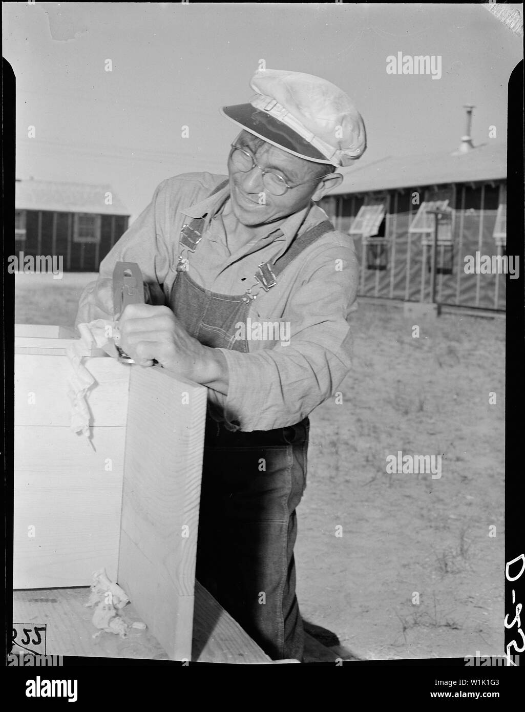 Tule Lake Relocation Center, Newell, California. Shinkichi Kyono, 56, carpenter-evacuee from Longvi . . .; Scope and content:  The full caption for this photograph reads: Tule Lake Relocation Center, Newell, California. Shinkichi Kyono, 56, carpenter-evacuee from Longview, Washington, is shown using a carpenter's plane which he won as first prize in a furniture contest conducted among the evacuees of Japanese descent at this War Relocation Authority center. Stock Photo