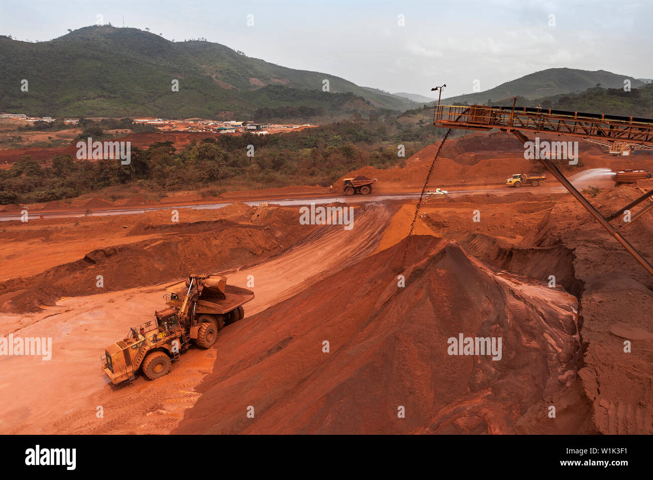 Mining operations for transporting and managing iron ore. Front end loader loading fines ore from stacker into dump truck for rail transport to port Stock Photo