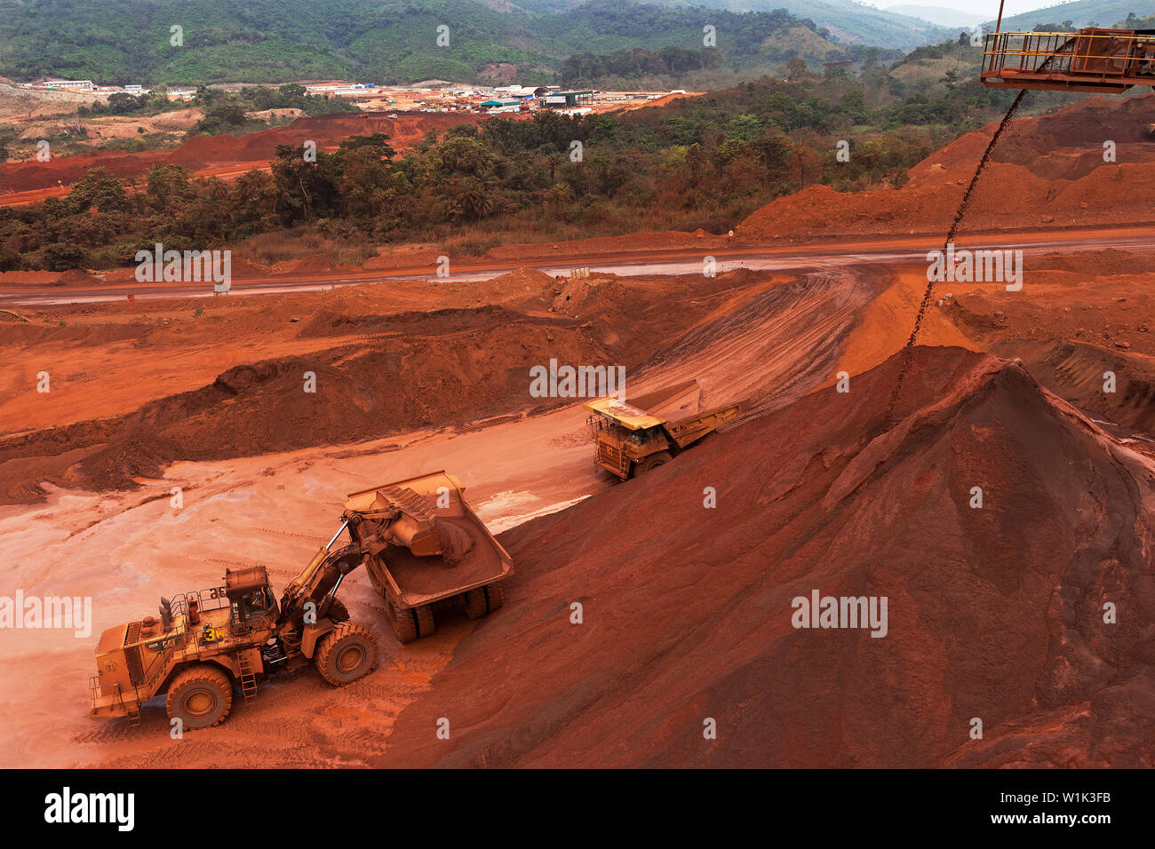 Mining operations for transporting and managing iron ore. Front end loader loading fines ore from stacker into dump truck for rail transport to port Stock Photo