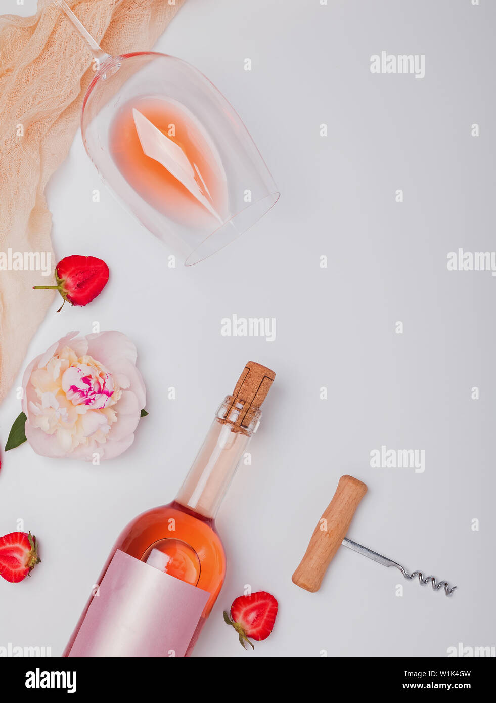 Creative summer flat lay with rose wine, delicious strawberries and beautiful peonies on the white background Stock Photo