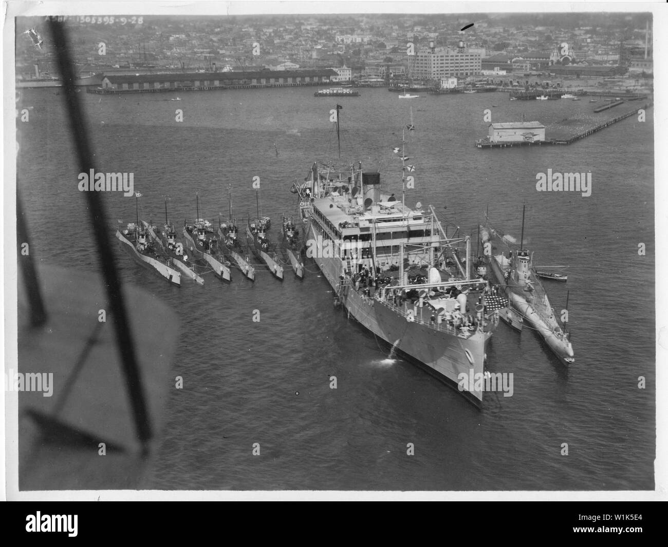 USS Argonne with S + Vec boat alongside; Aerial view of the USS Argonne in the harbor of the Destroyer Base, San Diego (today the Naval Base San Diego) in September 1928.  Several submarines are alongside, on the starboard side six S class submarines (left to right, USS S-46, probably USS S-45, USS S-43, USS S-44, USS S-47, and unidentified), and on the port side, one more S class and one Barracuda type V boat (either the V-1, V-2, or V-3). Stock Photo