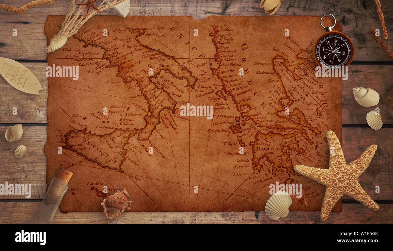 A piece of an old marine map on a wooden table surrounded by sea things, compass and an old bottle. Stock Photo