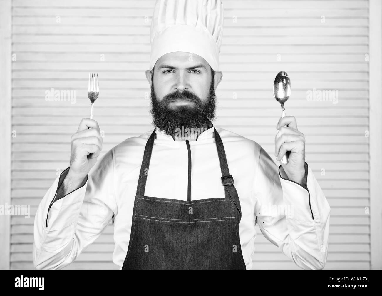 Chef serious face hold spoon and fork. Man handsome with beard ...