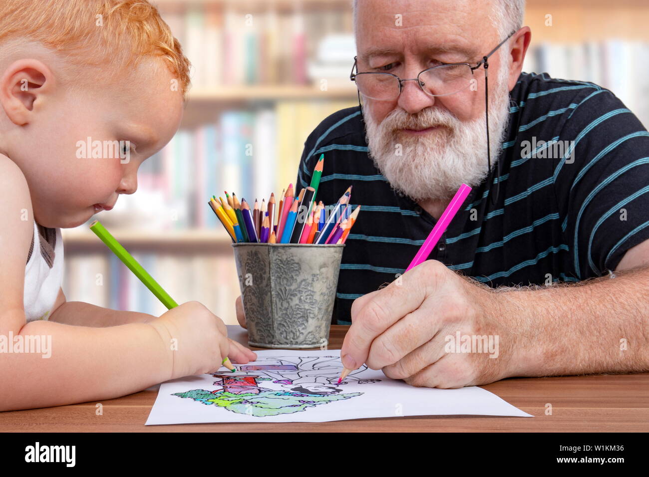 Grandpa working together and coloring on a drawing with his little grandson Stock Photo