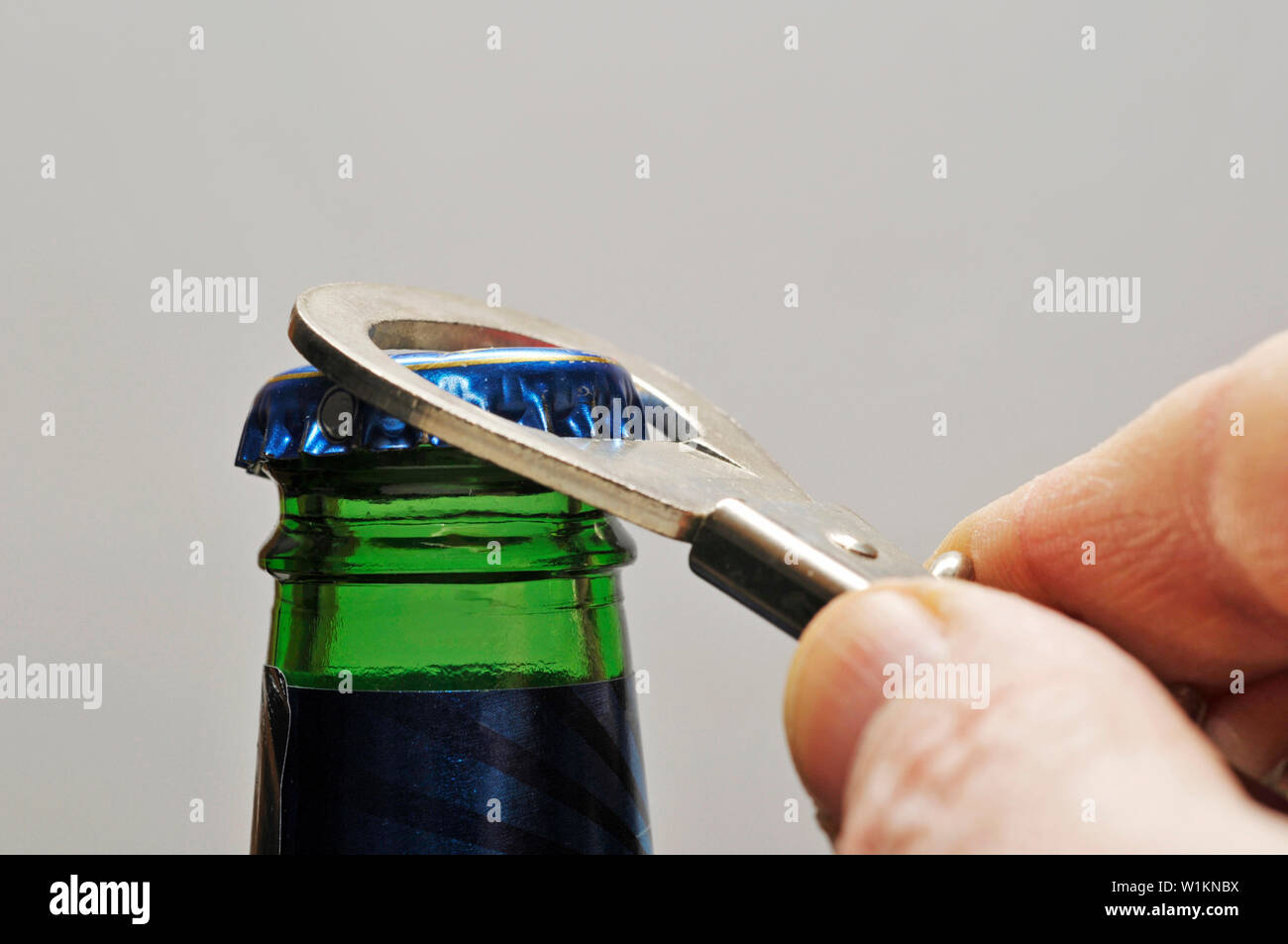 opening a beer bottle with an opener Stock Photo