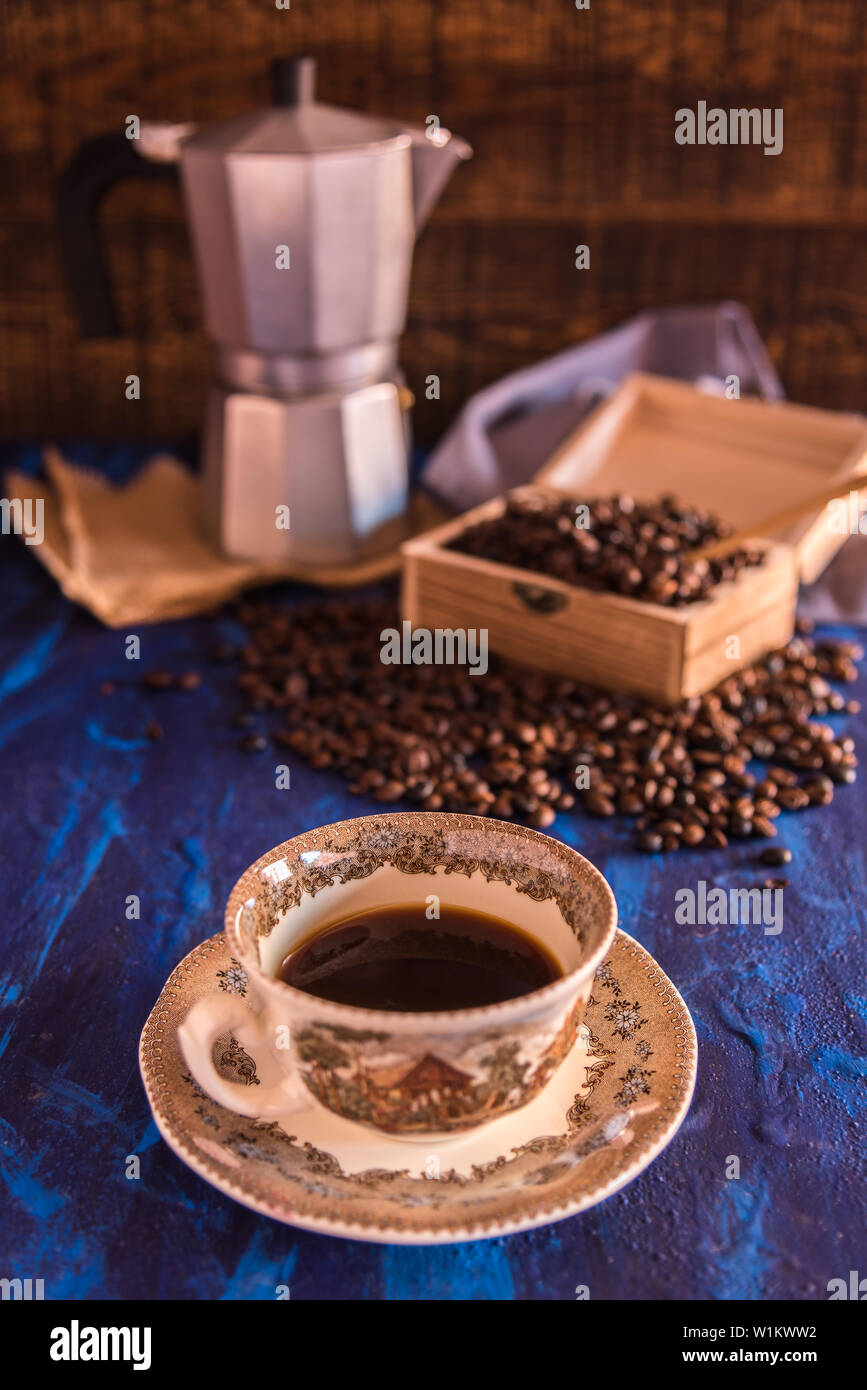 Freshly made coffee served in a cup and coffee beans in a wooden box on a blue background Stock Photo