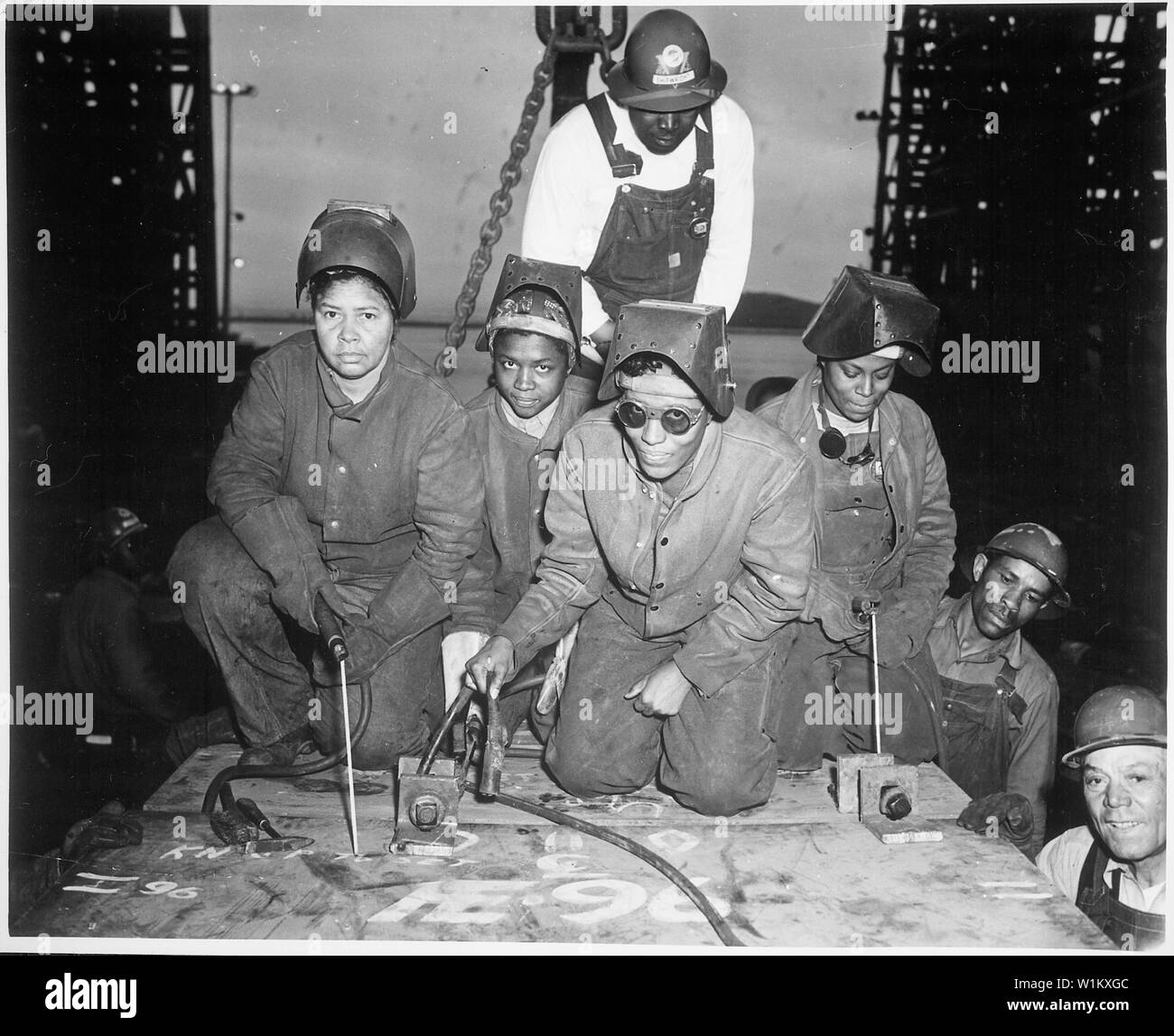 ... Welders Alivia Scott, Hattie Carpenter, and Flossie Burtos await an opportunity to weld their first piece of steel on the ship [SS George Washington Carver]., ca. 1943 Stock Photo