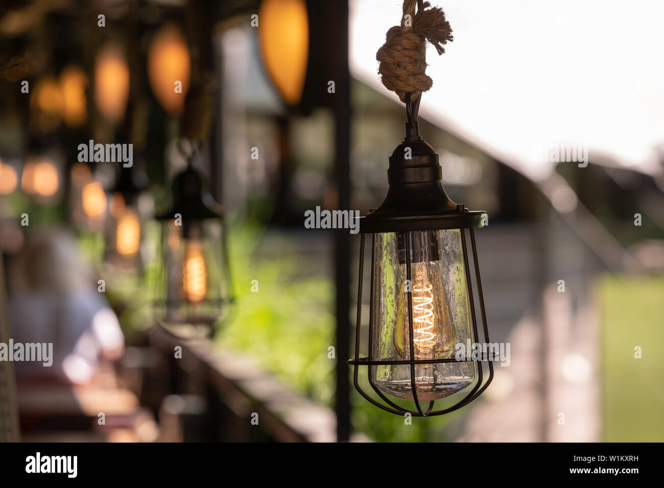 Description: Vintage decor lighting. Metal lamp with antique lamp hanging on a thick rope Stock Photo