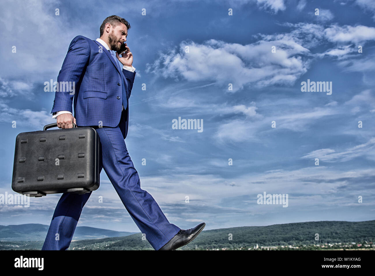 Keep going towards your goal. Businessman formal suit carries briefcase sky background. Businessman solving business problems on phone. Never stop. Entrepreneur in motion purposeful expression. Stock Photo