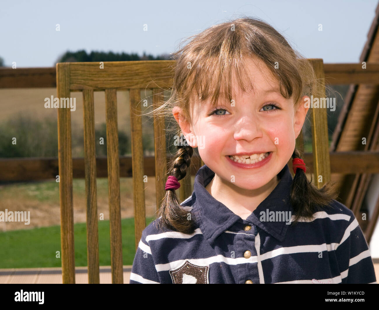 Smiling little girl sitting on chair Stock Photo - Alamy