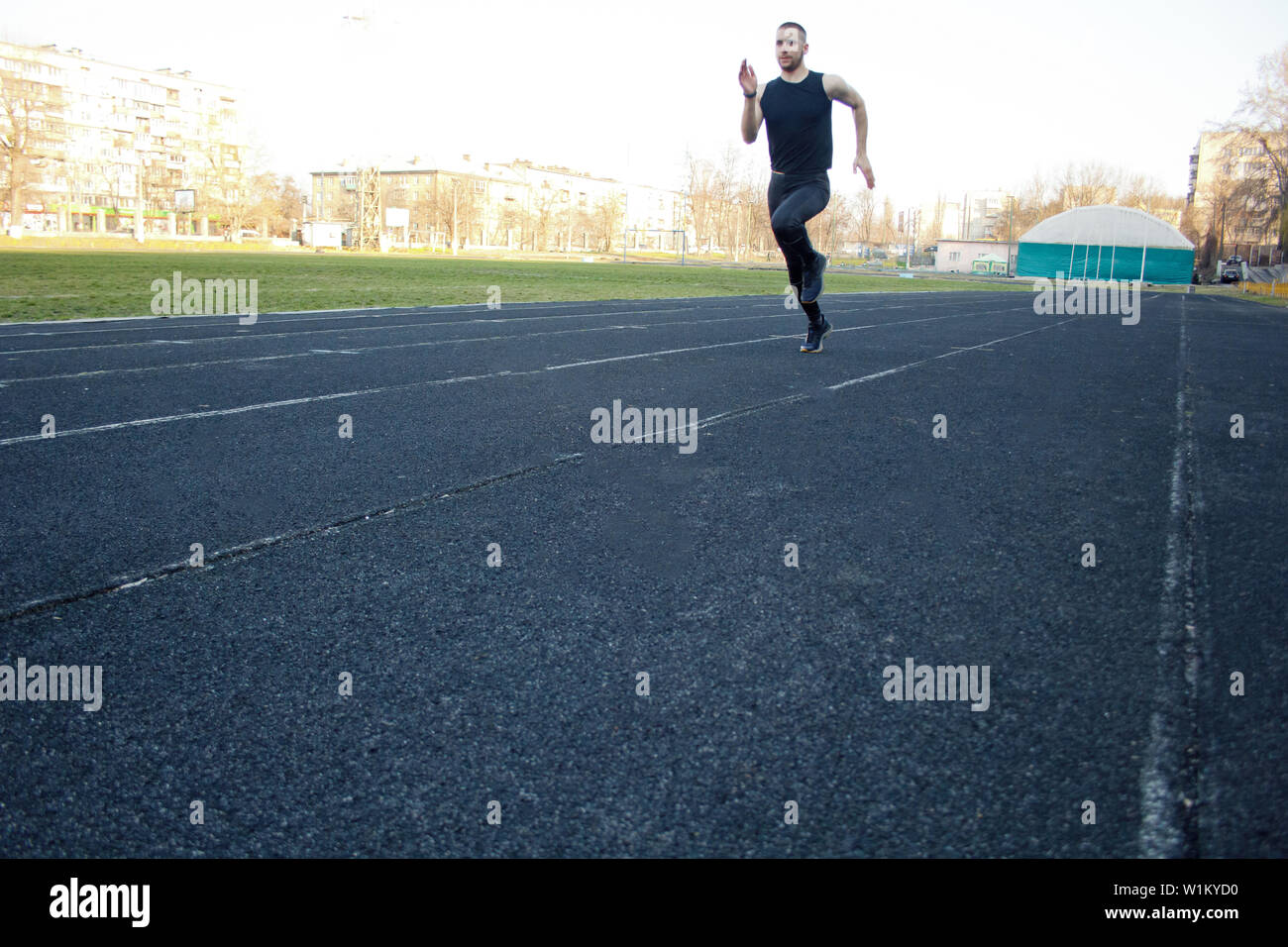 one caucasian male is doing a sprint start. running on the rubber track. Track and field runner in sport uniform. energetic physical activities. outdo Stock Photo