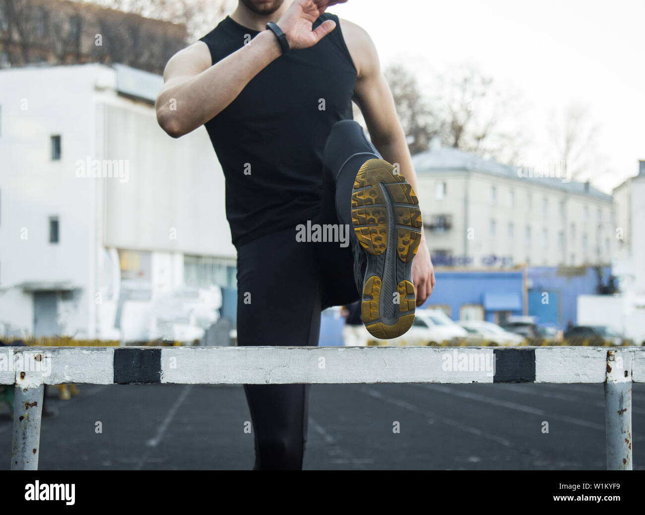 A man in black clothes is exercising outdoors with a barrier. fitness