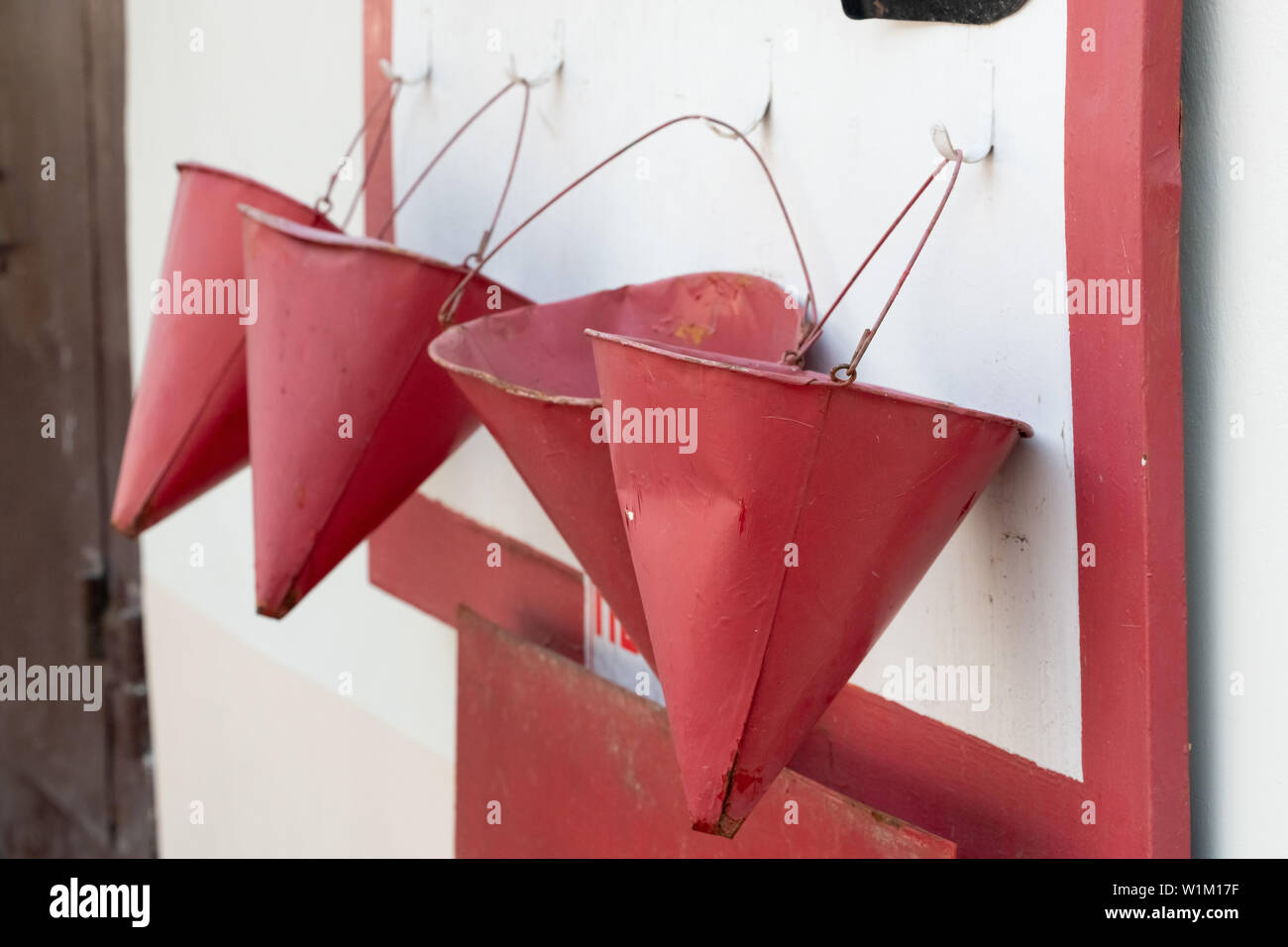 description: red bucket to fight the fire. a red bucket is hanging on a fire shield Stock Photo