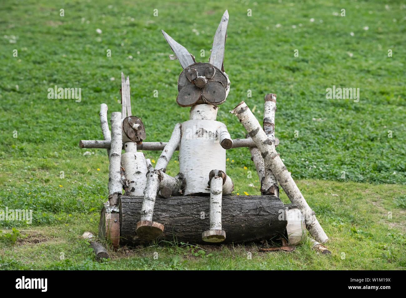description: hand-made wooden sculpture of birch on the background of grass in the Park Stock Photo