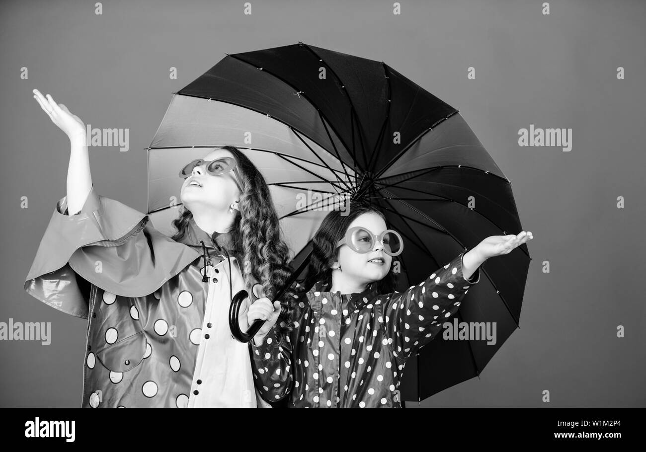 family bonds. Small girls in raincoat. happy small girls with colorful umbrella. rain protection. Rainbow. autumn fashion. cheerful hipster children, sisterhood. Feeling the beauty of nature. Stock Photo