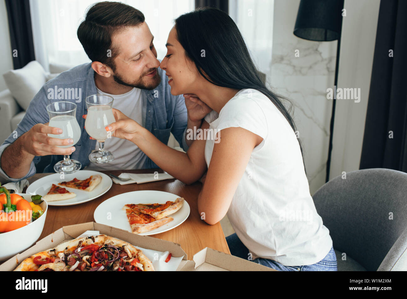 Happy couple kissing and have dinner with pizza at home. Its a good time spending home Stock Photo