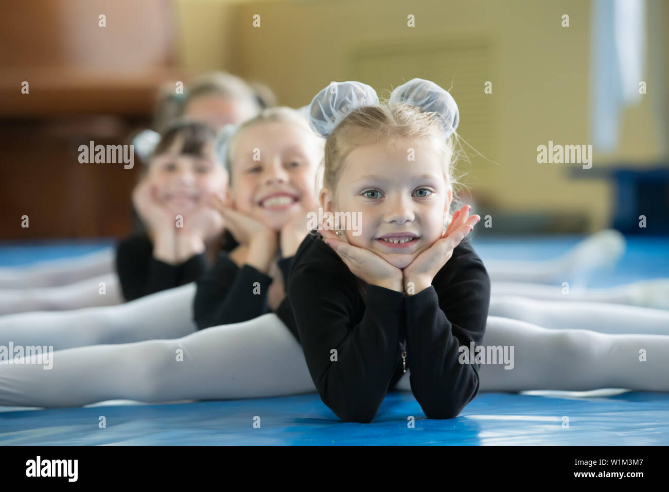 little girls gymnastic training Little girls gymnasts sit on the splits. Children do physical exercise.  Young ballerinas.. Training of the initial group on gymnastics.Acrobatics  less Stock Photo - Alamy