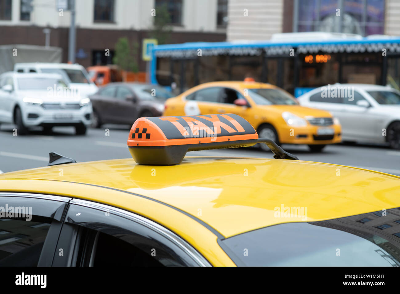 description: Yellow cab with taxi sign on the roof parked on the city street waiting for passengers to pick up.The taxi is parked on the street of the Stock Photo