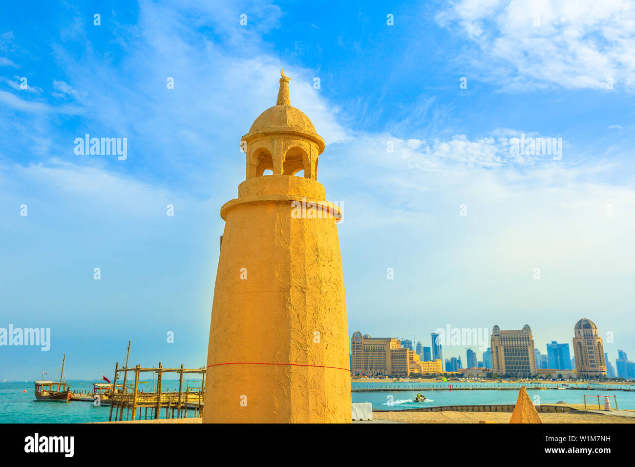 Katara Beach lighthouse with wooden boats and West Bay skyline on background in Doha Bay area near Katara cultural village. Qatar, Middle East Stock Photo