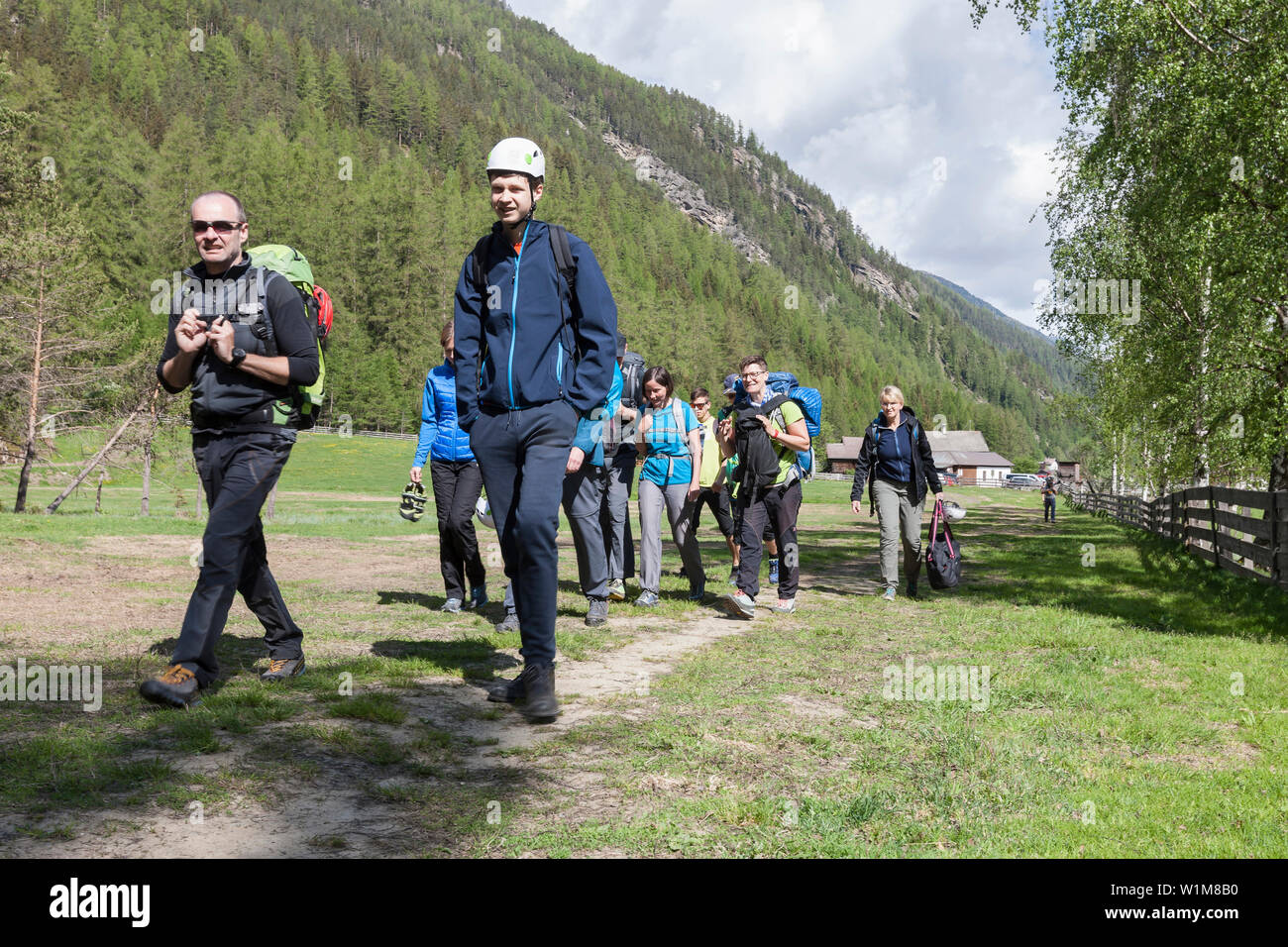 Group of climbers hiking through meadow towards Oberried climbing garden, Otztal, Tyrol, Austria Stock Photo