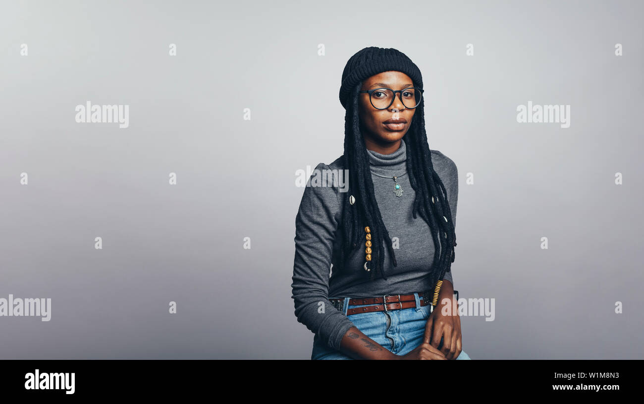 African woman isolated on grey background. Portrait of african female with long dreadlocks looking at camera. Stock Photo