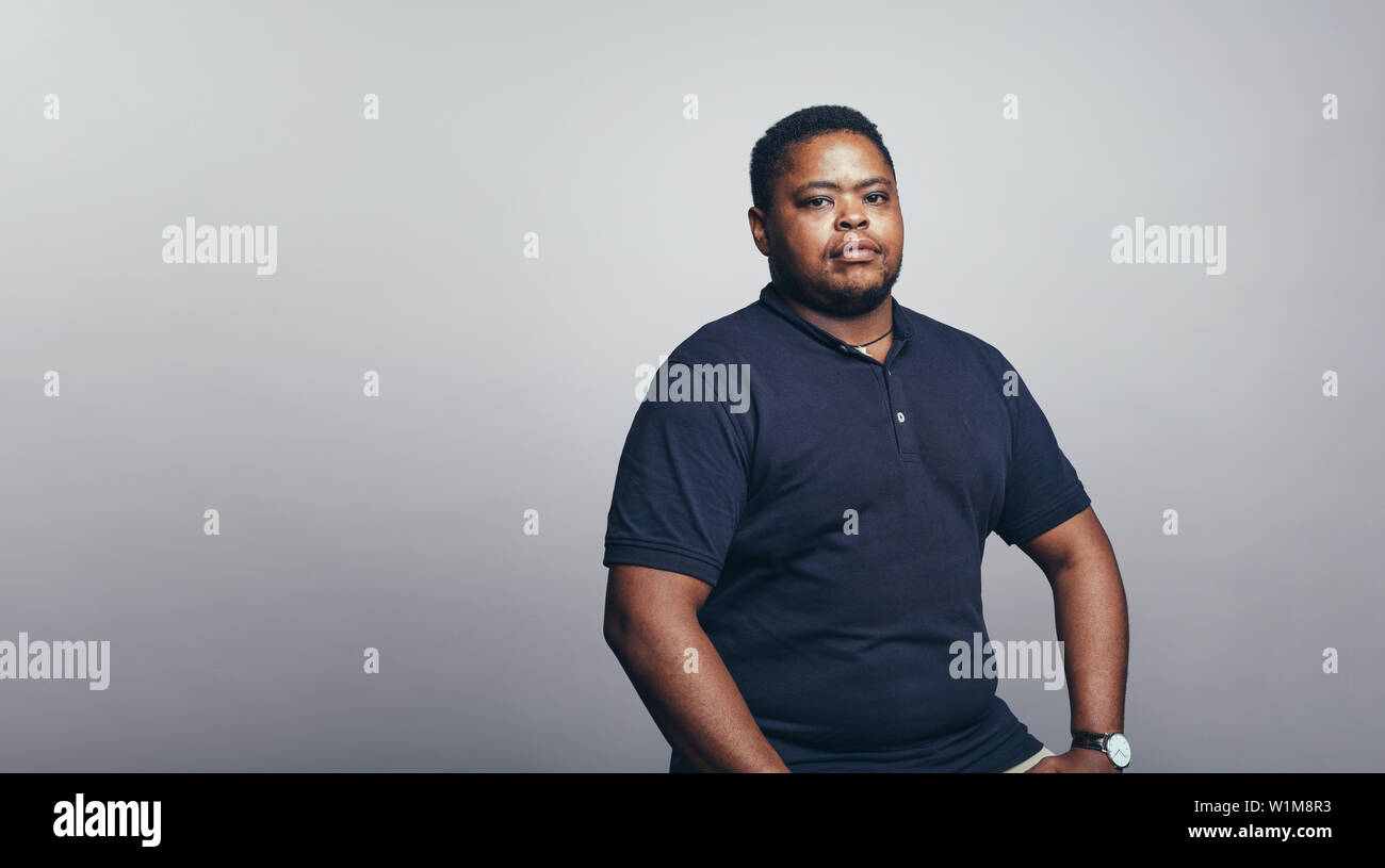 Portrait of man looking at camera. Strong african man against grey background. Stock Photo