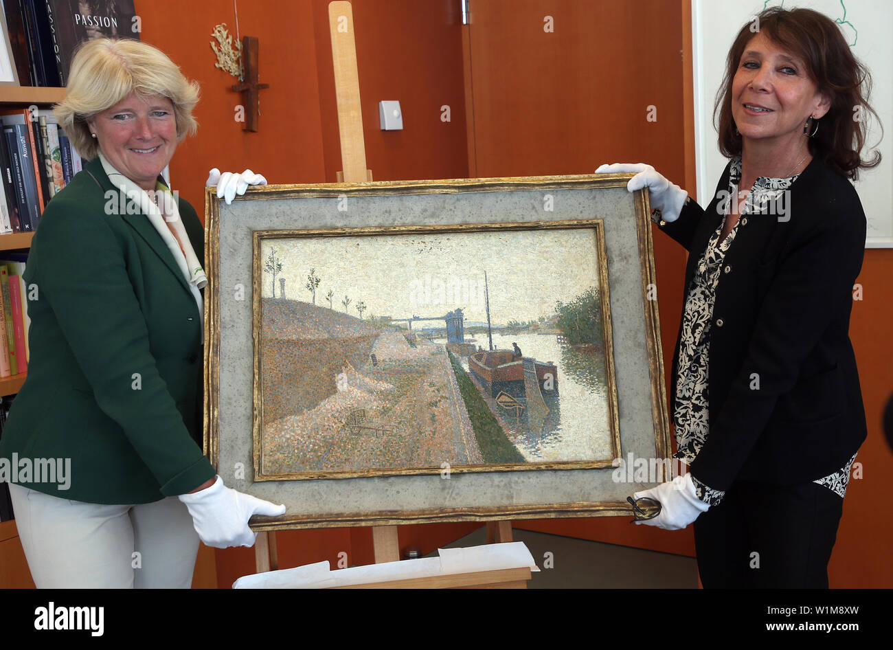 03 July 2019, Berlin: Minister of Culture Monika Grütters (CDU) hands over the painting 'Quai de Clichy' by the French painter Paul Signac (1863-1935) to Agnes Sevestre-Barbe (r), the representative of the heiress, as part of the return of Nazi looted art from the Gurlitt art collection. Large parts of Cornelius Gurlitt's collection were suspected of having been stolen from Jewish owners during the Nazi era. So far, only seven of the approximately 1500 works of art have clearly proved to be Nazi looted art. Photo: Wolfgang Kumm/dpa - ATTENTION: Only for editorial use in connection with current Stock Photo