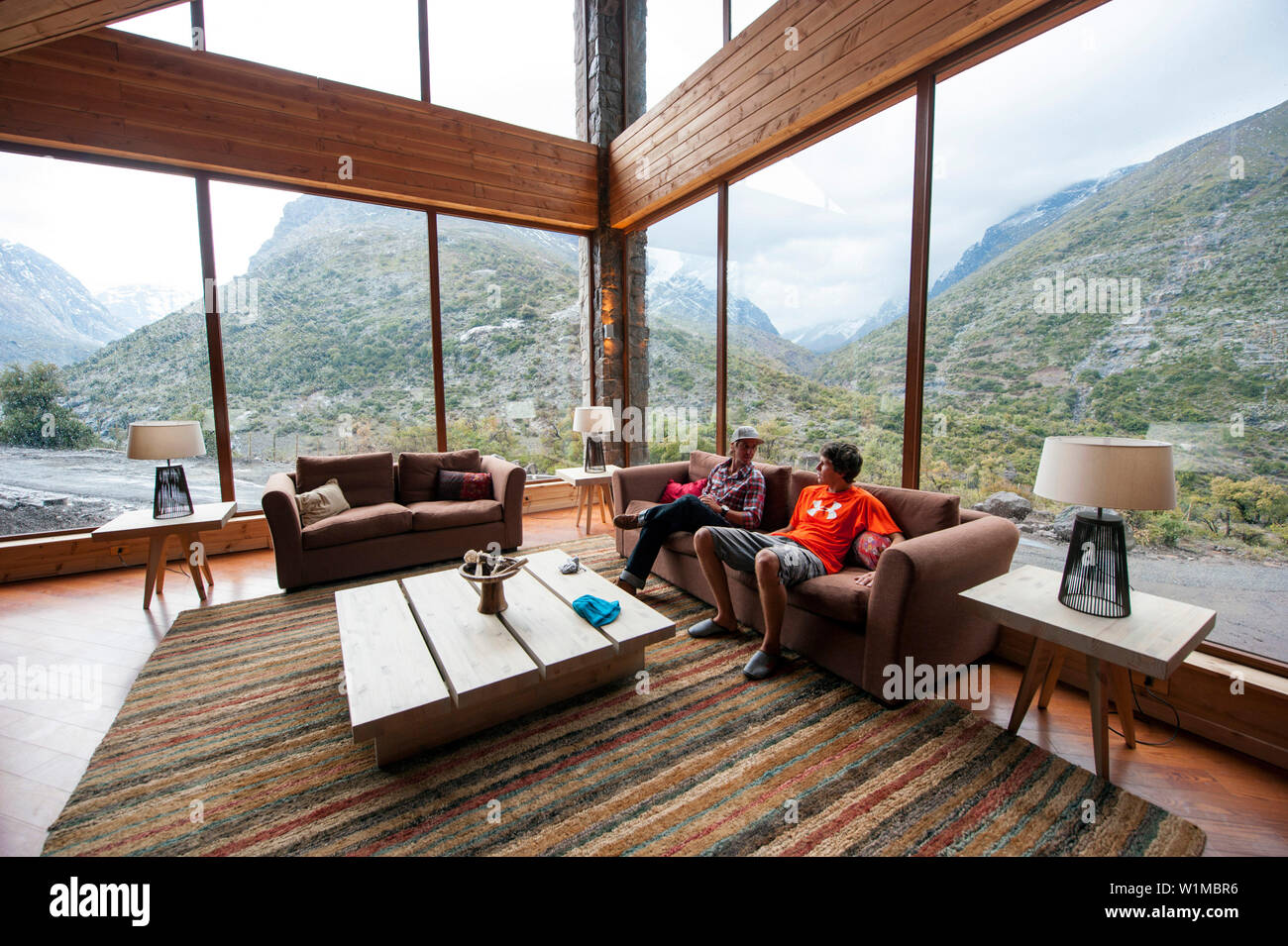 Two men sitting on a sofa in a lodge, Puma Lodge, Araucania Region, Chile  Stock Photo - Alamy
