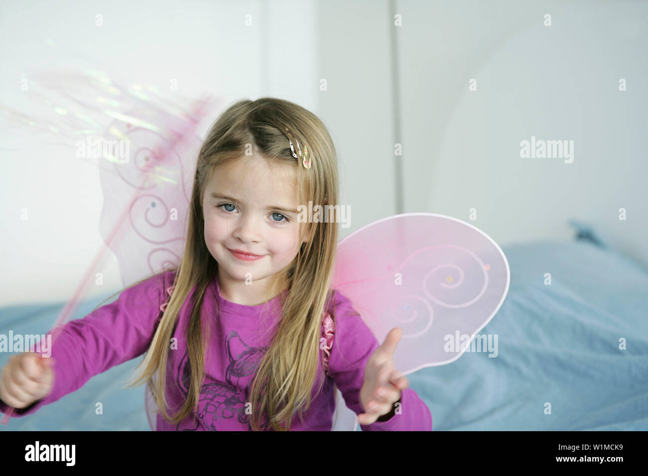 Girl (3-4 years) wearing butterfly wings holding wand, Munich, Germany Stock Photo