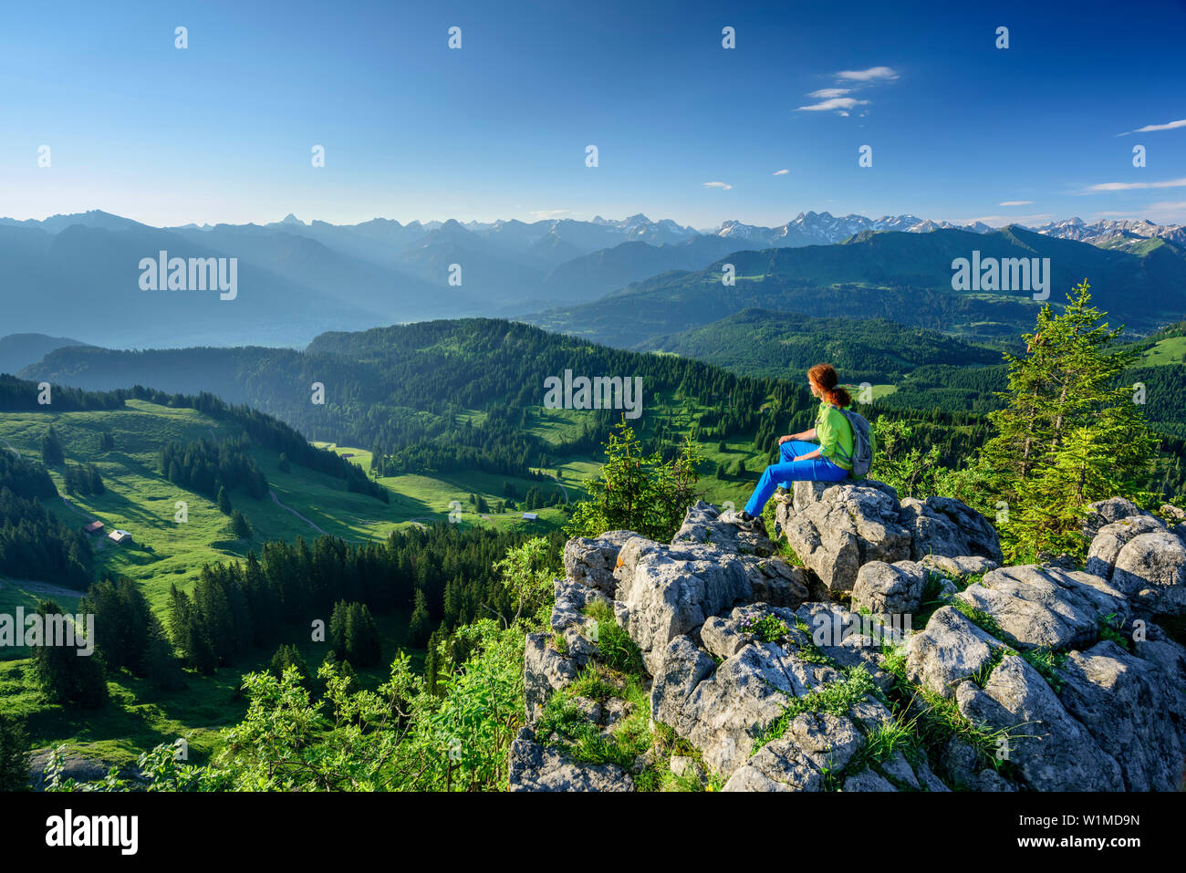 Woman hiking sitting on Besler and looking towards Allgaeu Alps, Besler, valley of Balderschwang, Allgaeu Alps, Allgaeu, Svabia, Bavaria, Germany Stock Photo