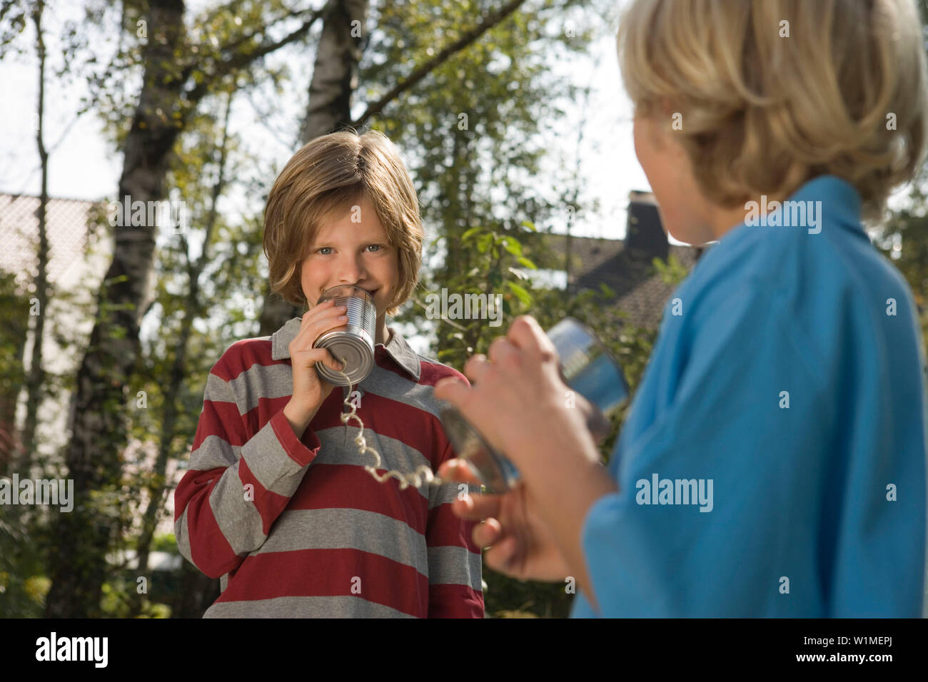 Two boys playing with a tin can phone, children's birthday party Stock Photo