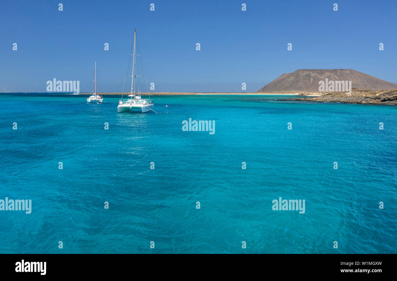 Sailing ships in turquoise sea in front of island Isla de la Lobos, Parque Nationale de los Lobos, Fuerteventura, Canary Islands, Spain Stock Photo