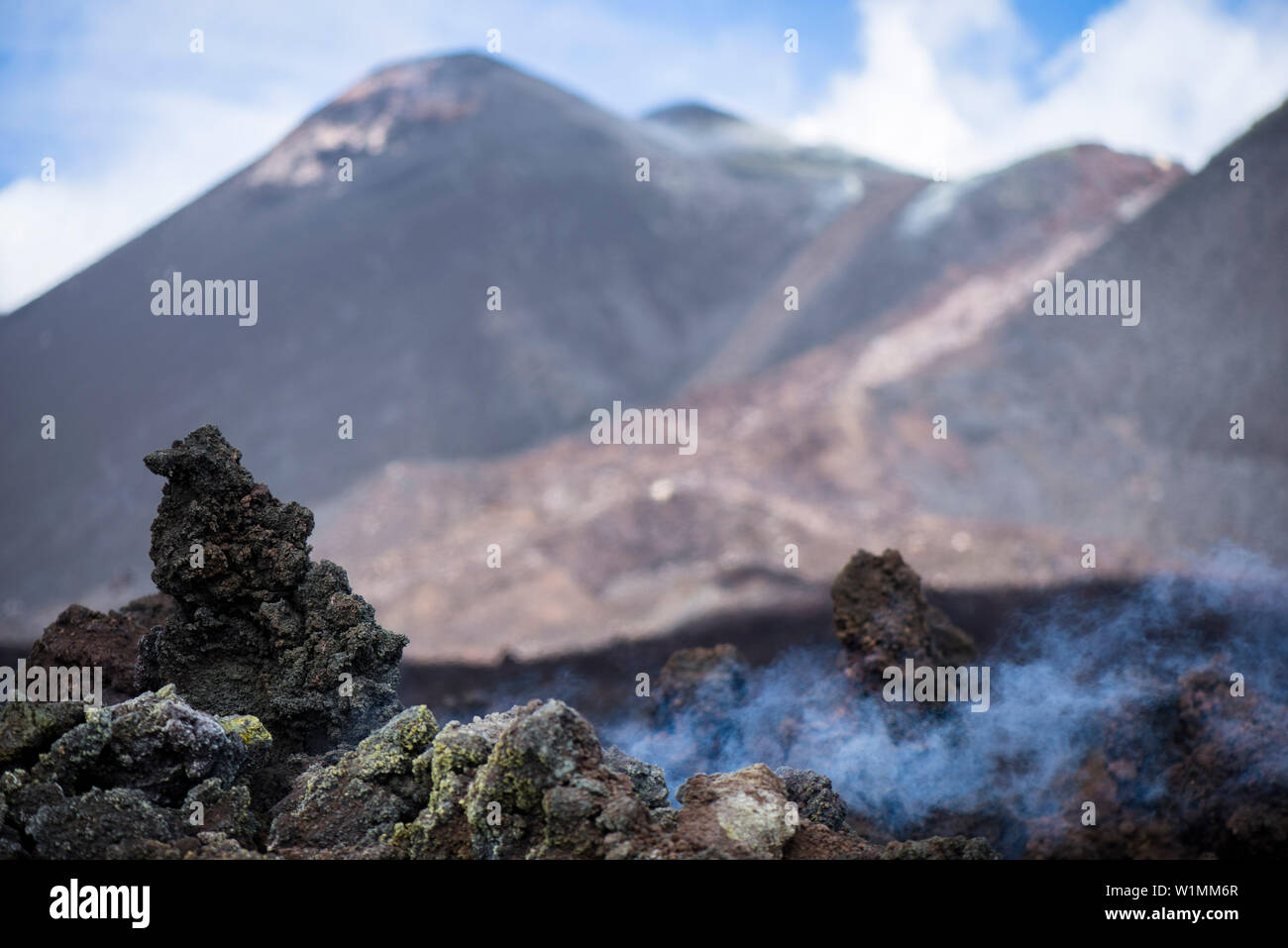 Solidified, steaming lava in front of the southeast crater of Etna volcano. Steam clouds are rising, Sicily, Italy Stock Photo