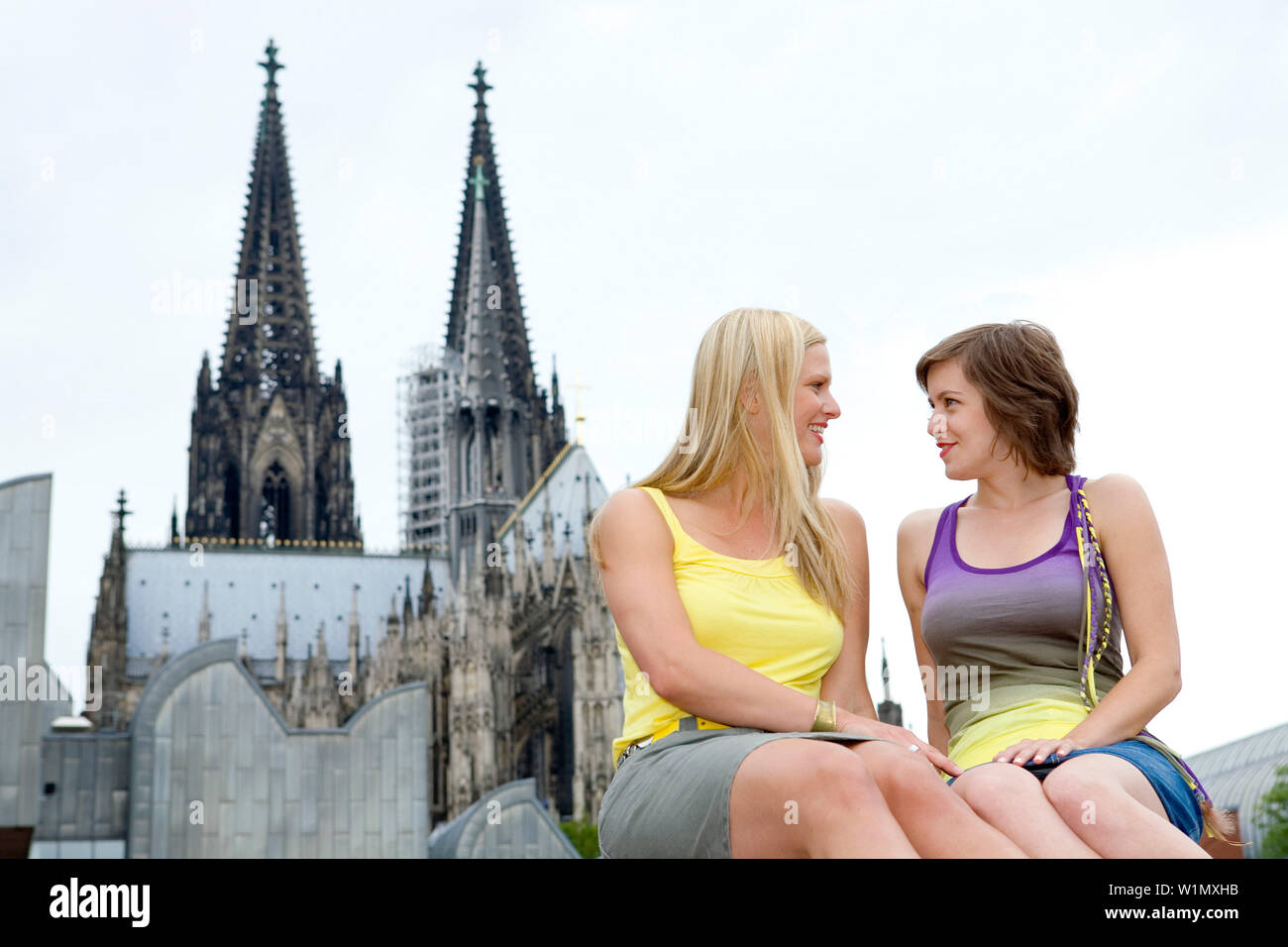 Two young german women sitting in front of the Cathedrale of Cologne, Cologne, North Rhine-Westphalia, Germany Stock Photo