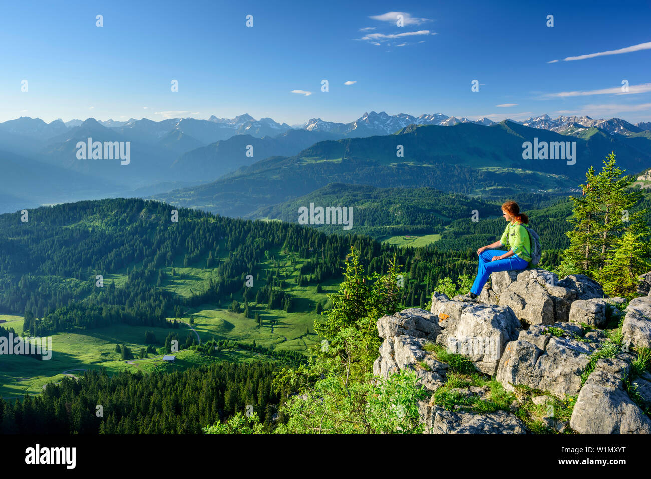 Woman hiking sitting on Besler and looking towards Allgaeu Alps, Besler, valley of Balderschwang, Allgaeu Alps, Allgaeu, Svabia, Bavaria, Germany Stock Photo