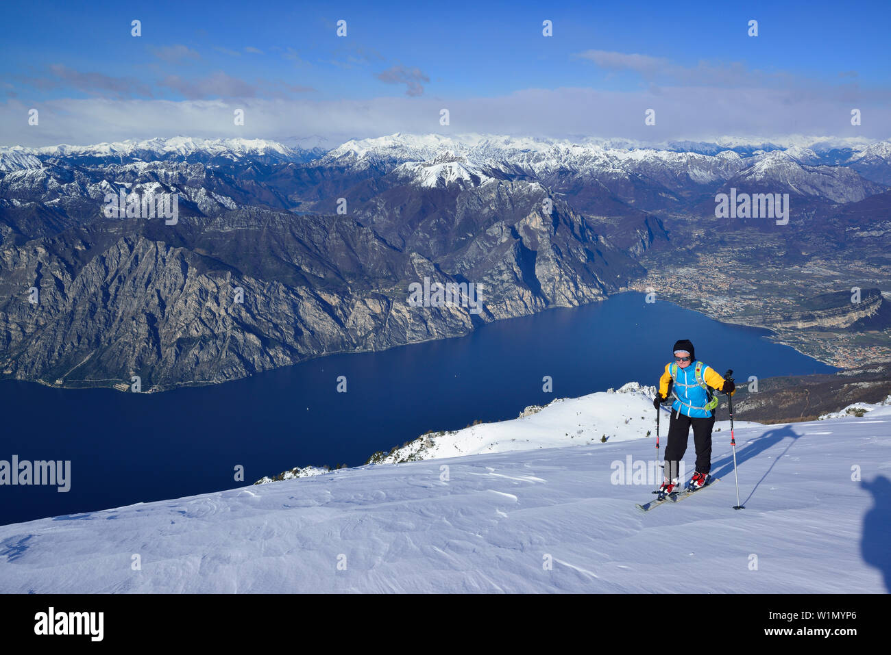Female back-country skier ascending to Monte Baldo, lake Garda in background, Monte Baldo, Garda Mountains, Trentino, Italy Stock Photo