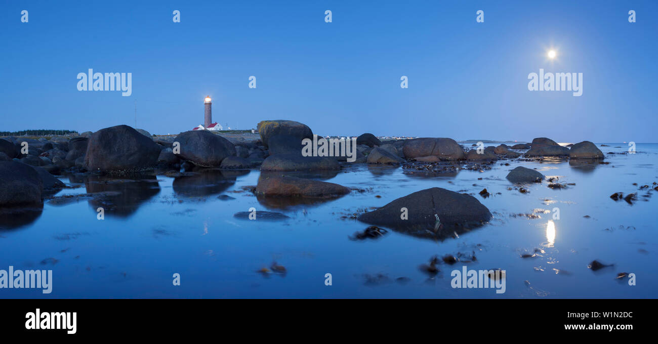 Gentle coast of the North Sea with the lighthouse Lista Lighthouse between boulders in blue twilight with moon, Farsund, Vest-Agder, Norway, Scandinav Stock Photo