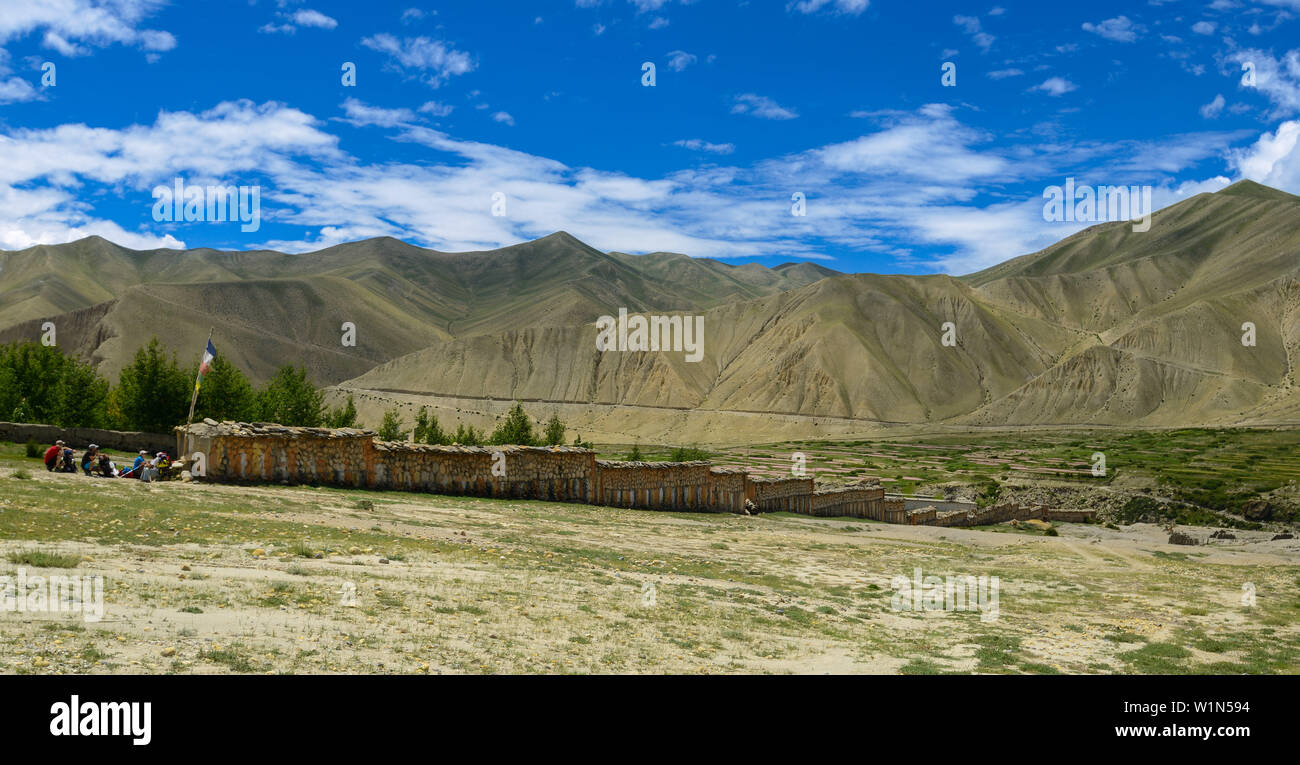 The longest Mani wall in the world with buddhist mantras in Sanskrit Om mani padme hum, carved in stone, group of hikers, trekkers at Ghami, Ghemi, ti Stock Photo