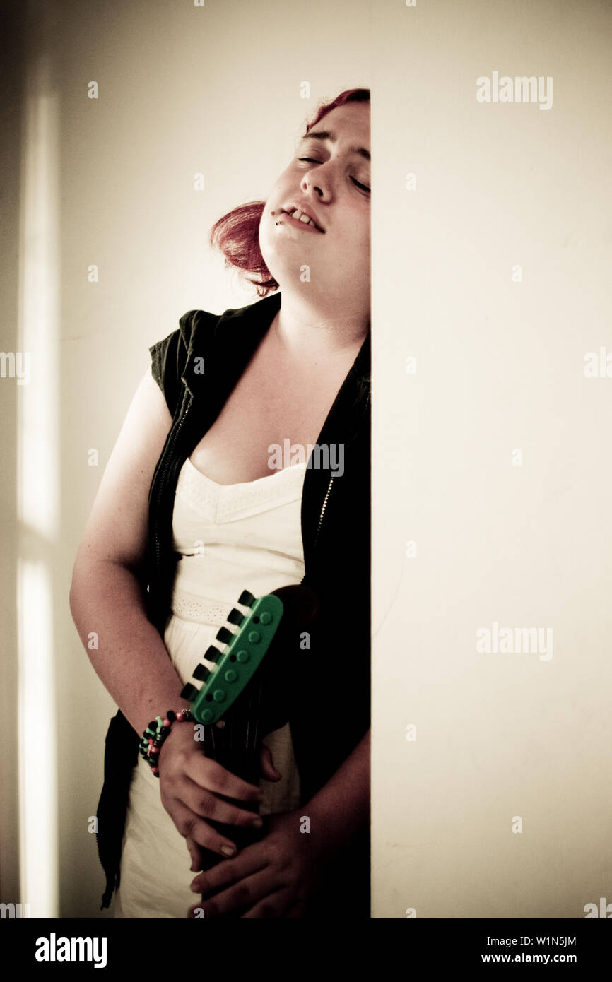 portrait of young female teen holding a guitar with a distressed look on her face Stock Photo
