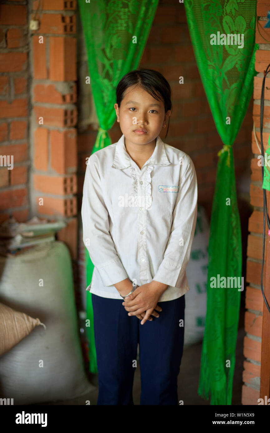 a Vietnamese teenage girl stands looking at the camera at her home in a village outside Ho Chi Minh City in South Vietnam Stock Photo