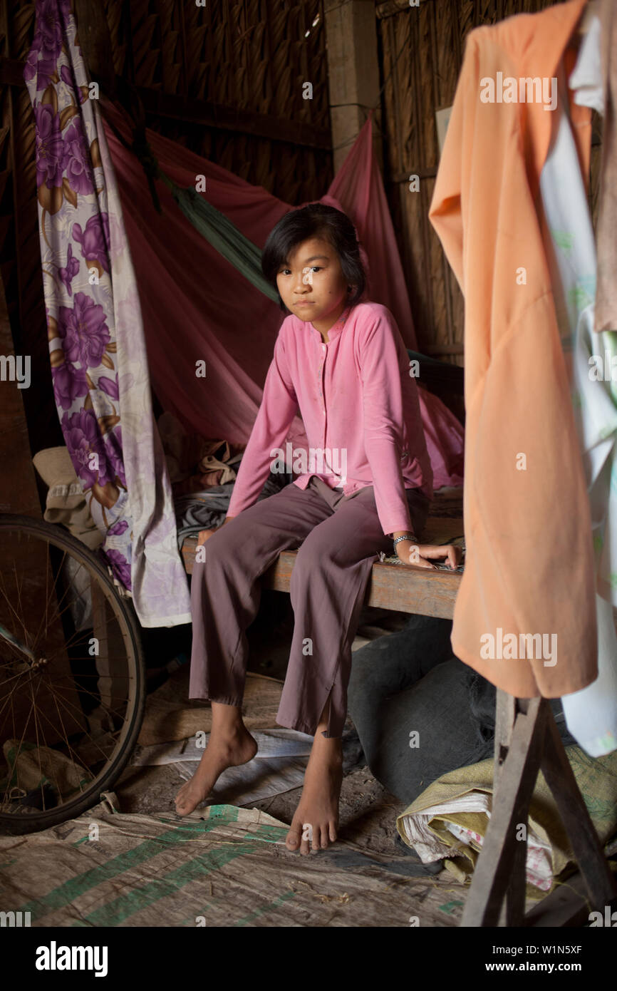 portrait of a young Vietnamese girl sitting on her bed in her home in a village outside of Ho Chi Minh city Stock Photo