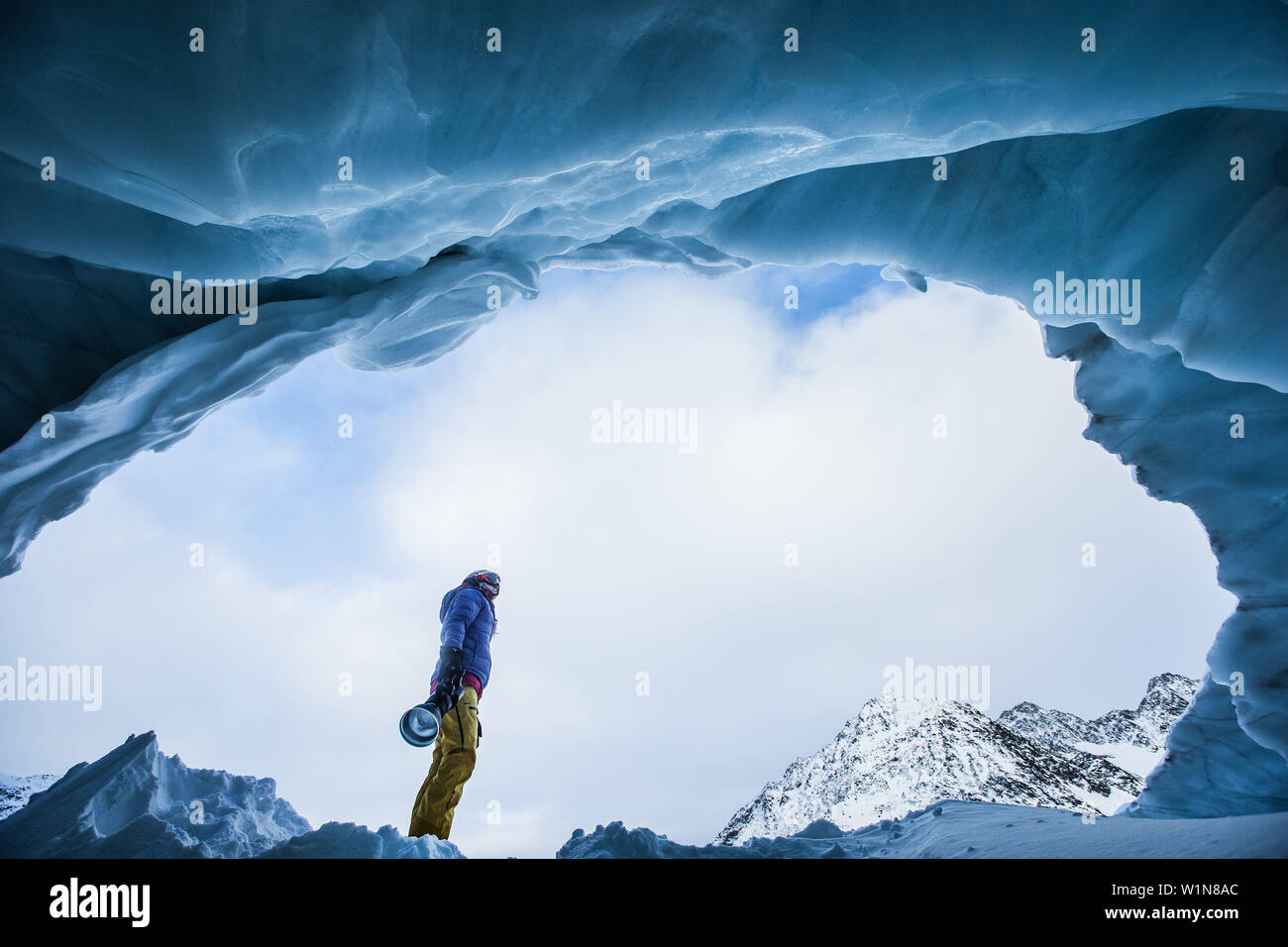 Young female freeskier standing in the cave of a glacier in the mountains, Pitztal, Tyrol, Austria Stock Photo