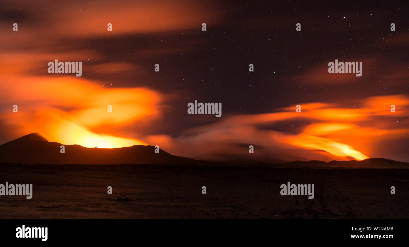 Views of the volcanoes Marum and Benbow at a distance at night. Lava illuminating the gases and the night sky is coloured as red as blood, Vanuatu, Am Stock Photo