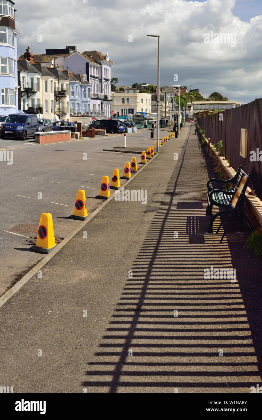 Shadows of metal railings and no-waiting cones along roadside parking bays. Stock Photo