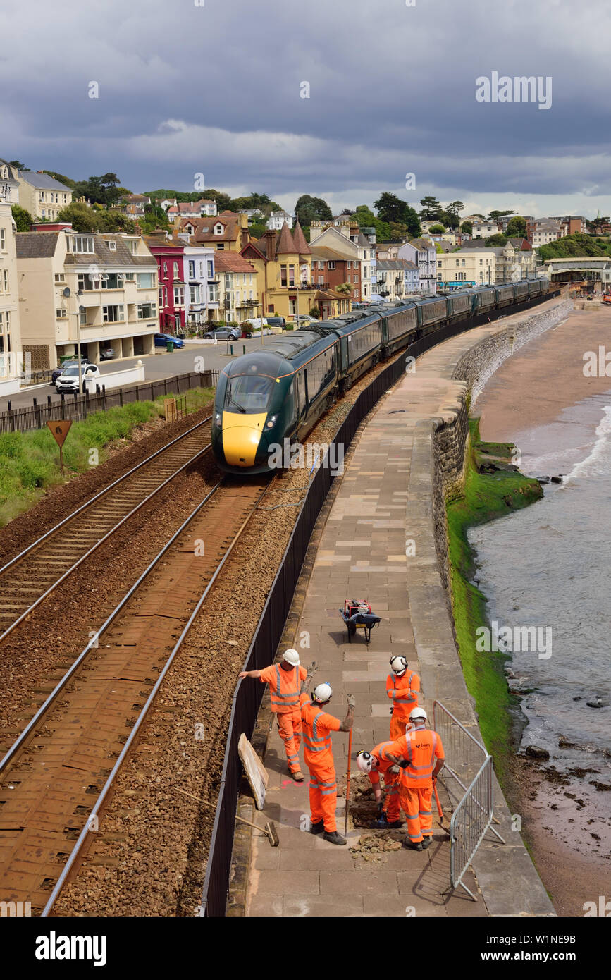 A GWR class 800 Inter-city express train passing through Dawlish as railway workmen begin preparatory work for raising the height of the seawall. Stock Photo