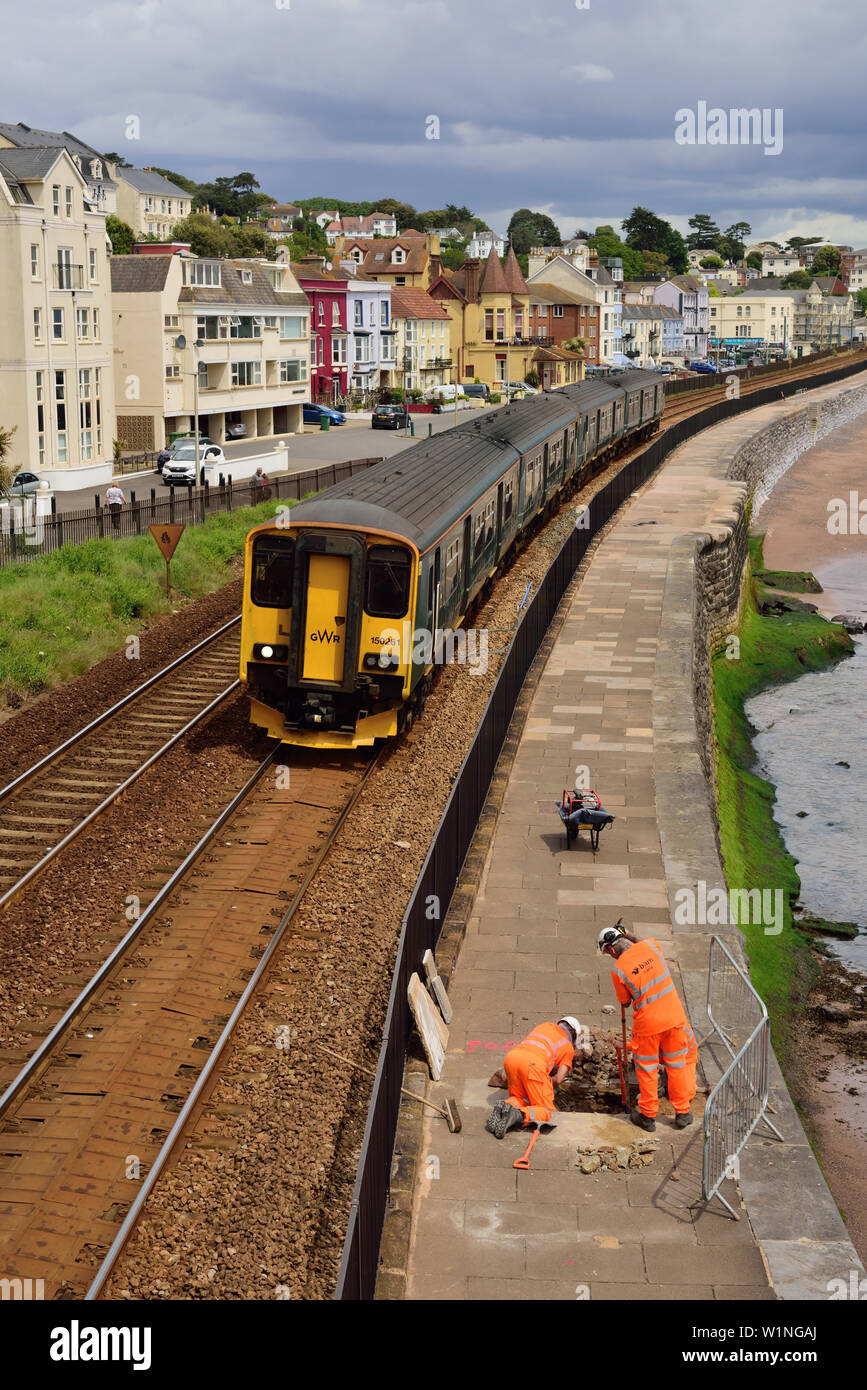 GWR multiple unit No 150261 passing through Dawlish where railway workers are doing preparatory work for raising the height of the seawall, 05.06.2019. Stock Photo